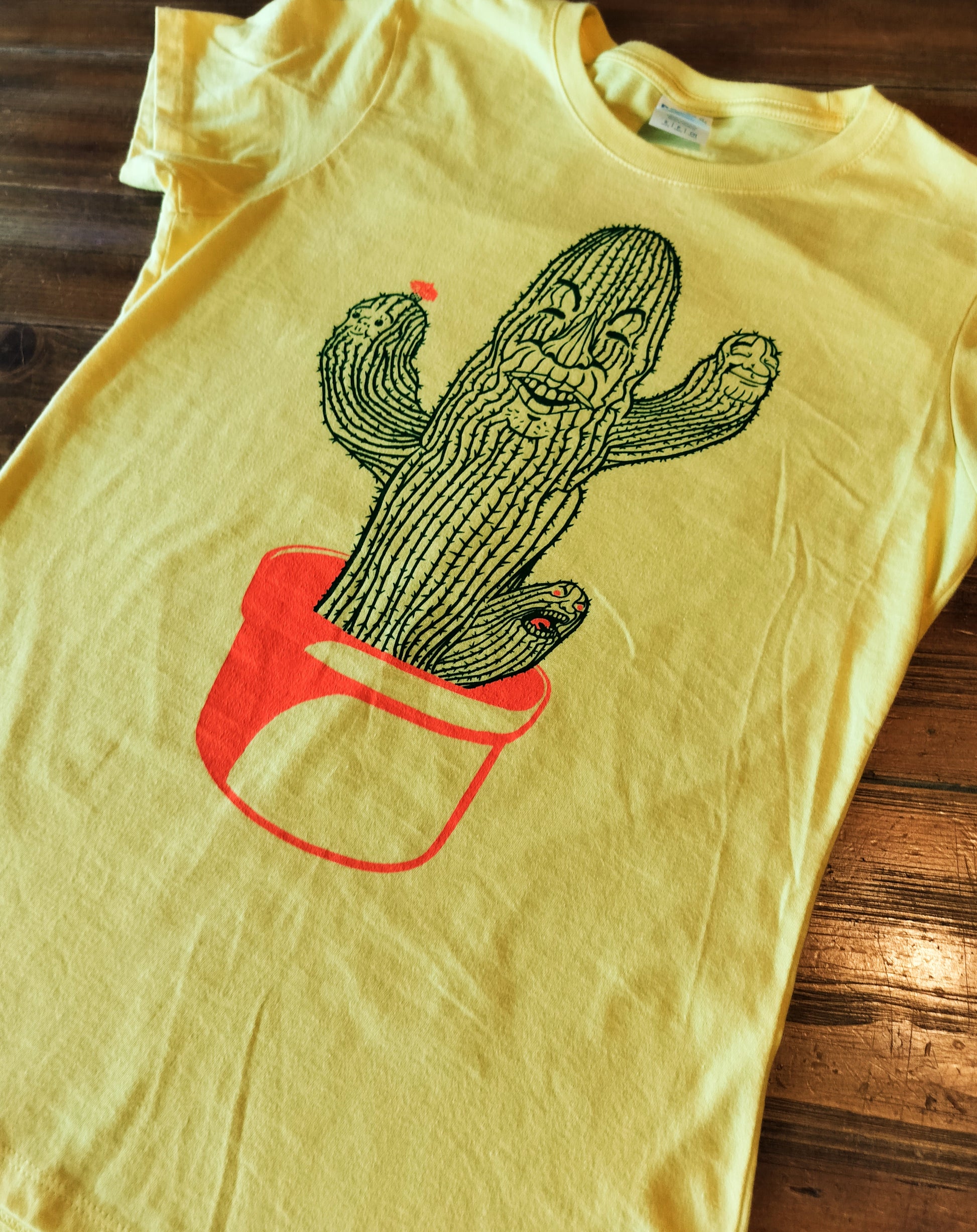 Yellow t-shirt with a cactus design on a wooden surface