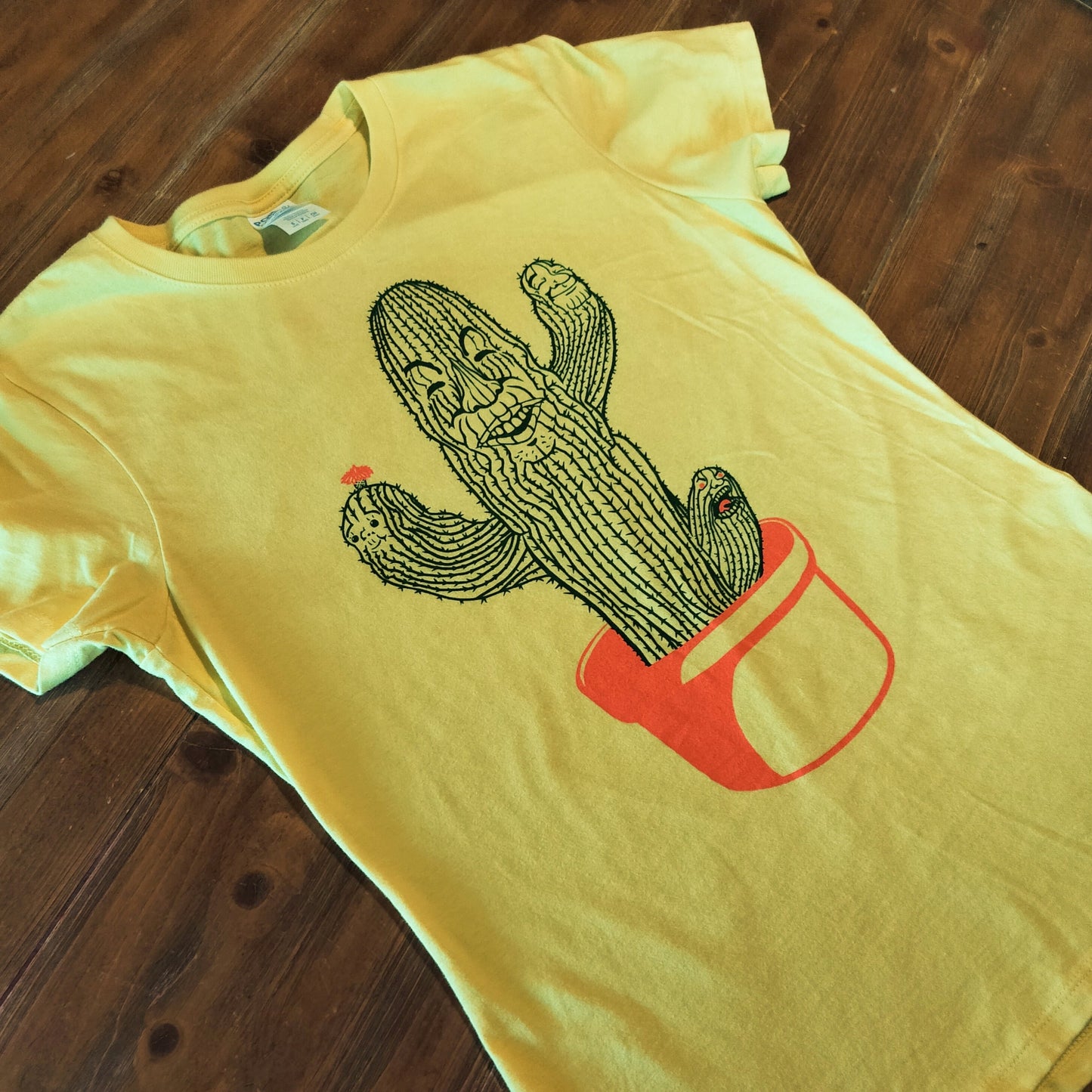 Yellow t-shirt with a cactus design on a wooden surface
