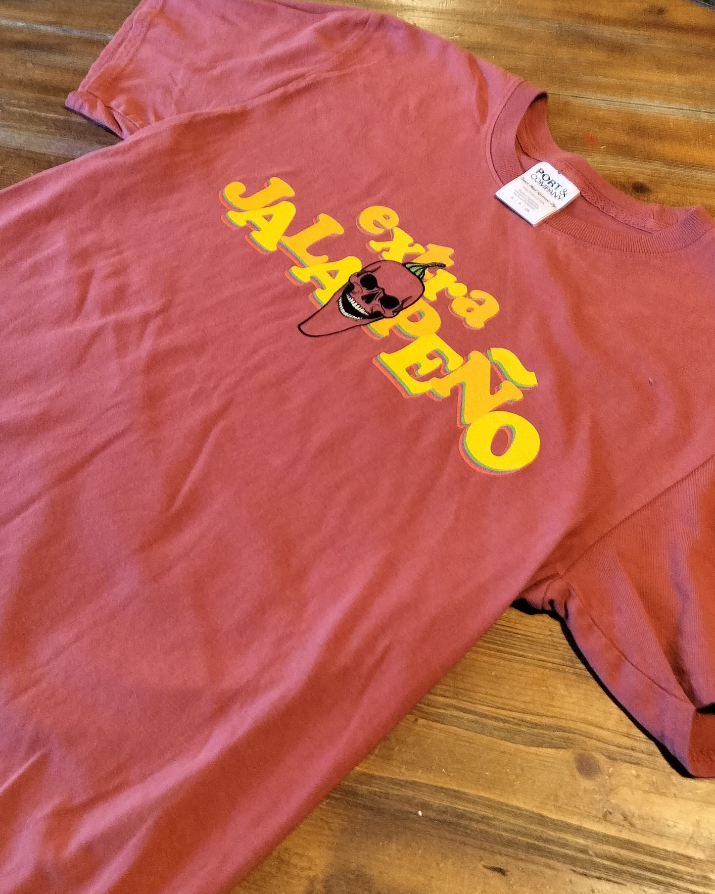 Red t-shirt with 'extra jalapeno' text on a wooden surface