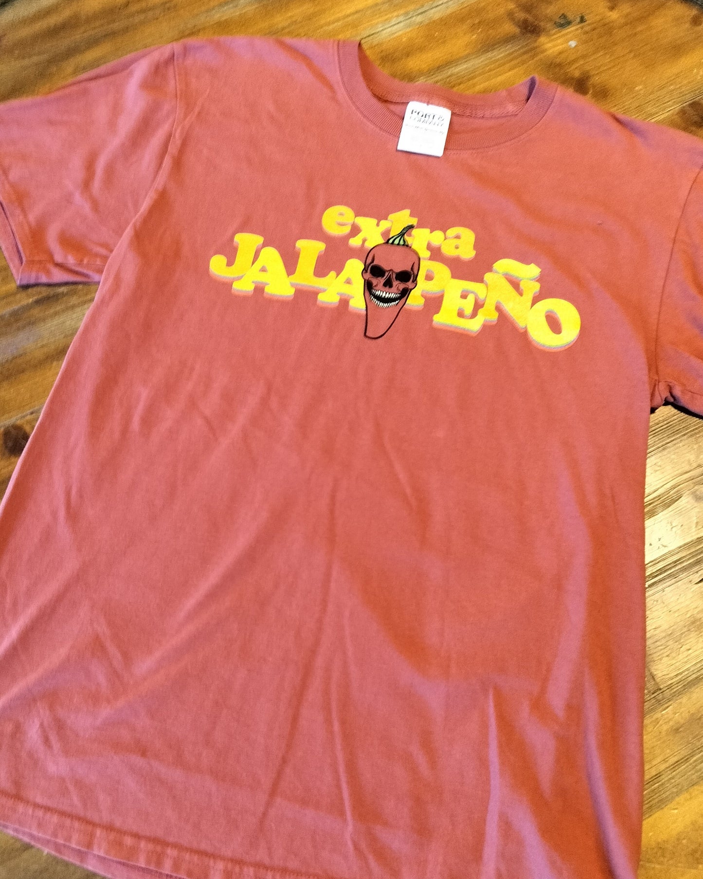 Red t-shirt with 'extra JALAPENO' text and pepper graphic on a wooden surface