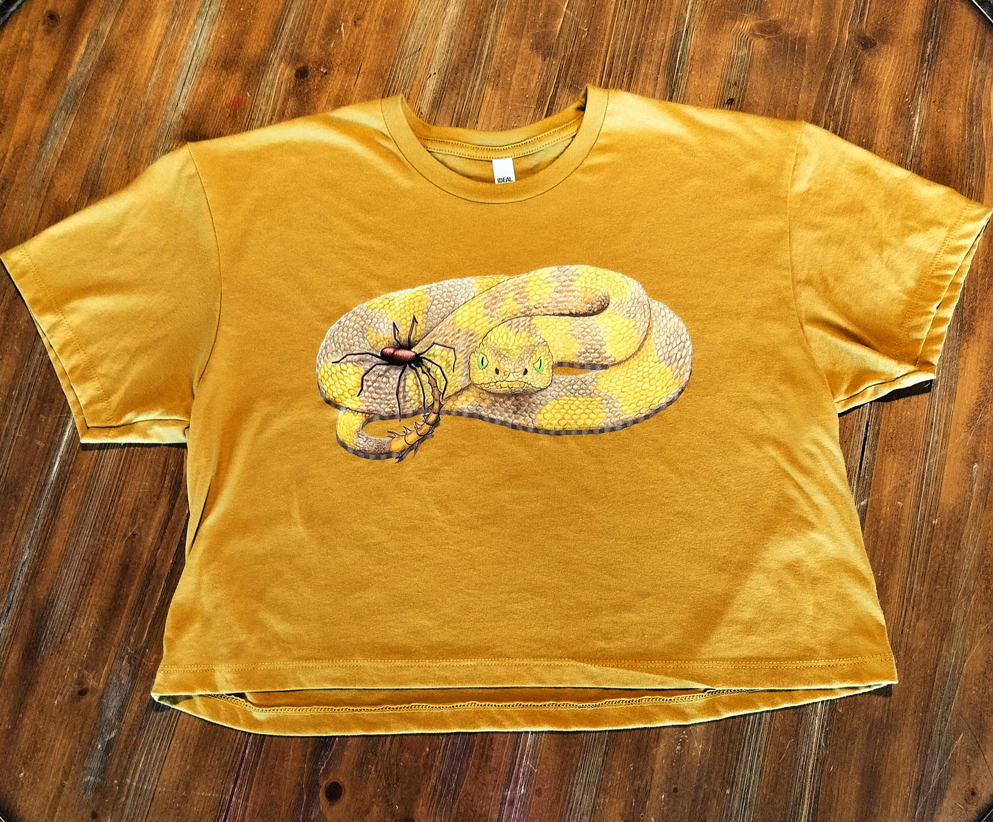 Yellow t-shirt with a snake graphic on a wooden surface