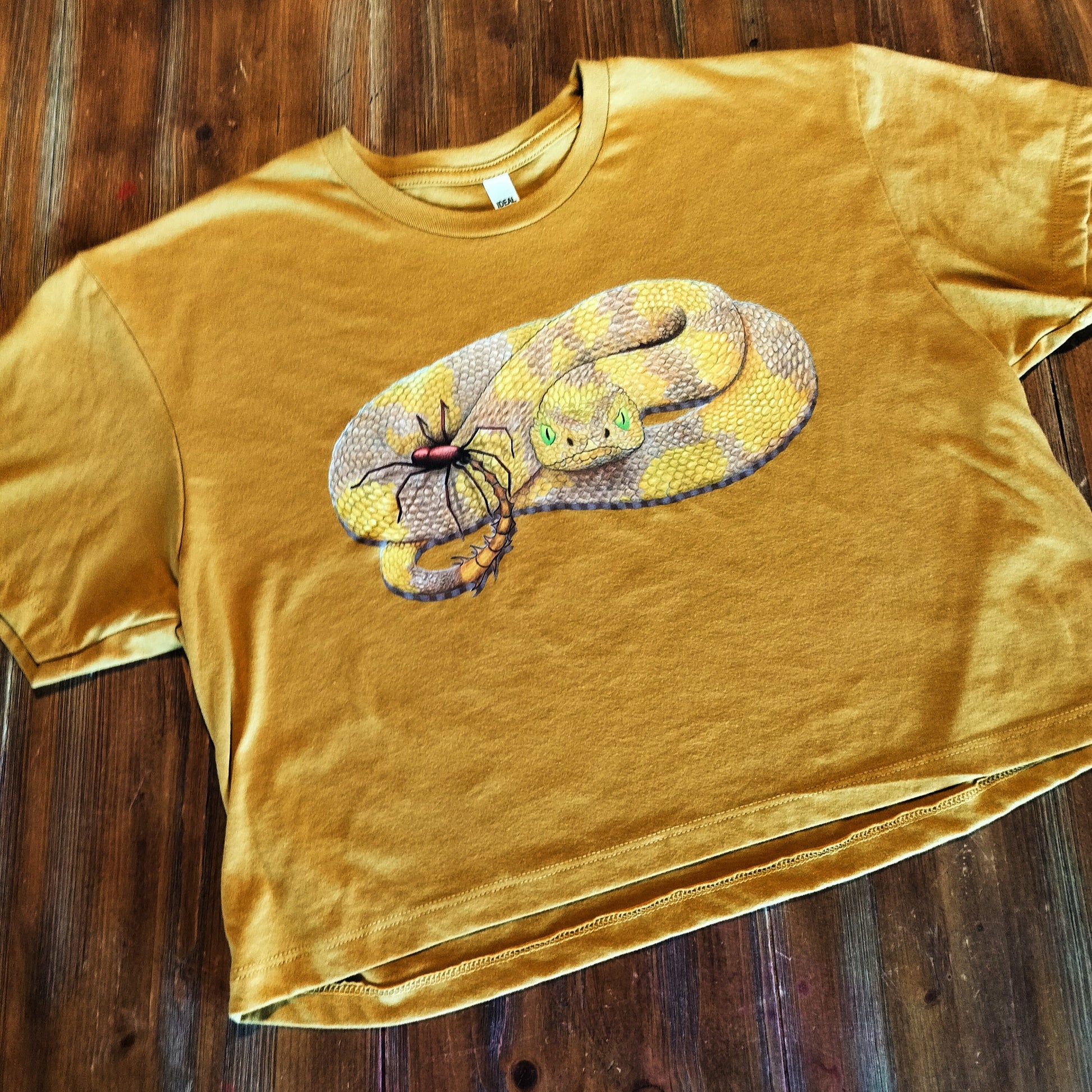 Yellow t-shirt with a snake graphic on a wooden surface
