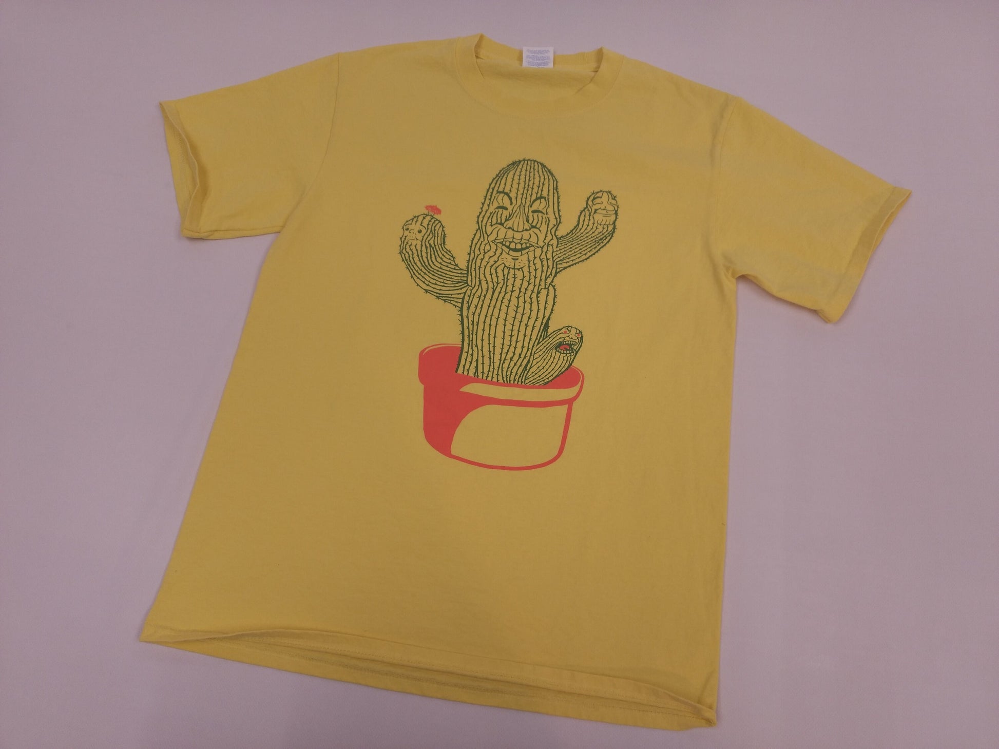 Yellow shirt featuring cactus design over plain white background