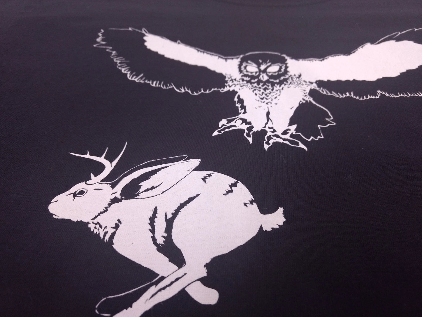 an illustration of a jackalope fleeing an owl attempting to scoop up the animal