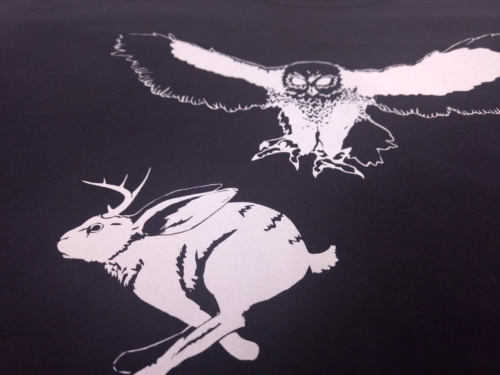 an illustration of a jackalope fleeing an owl attempting to scoop up the animal