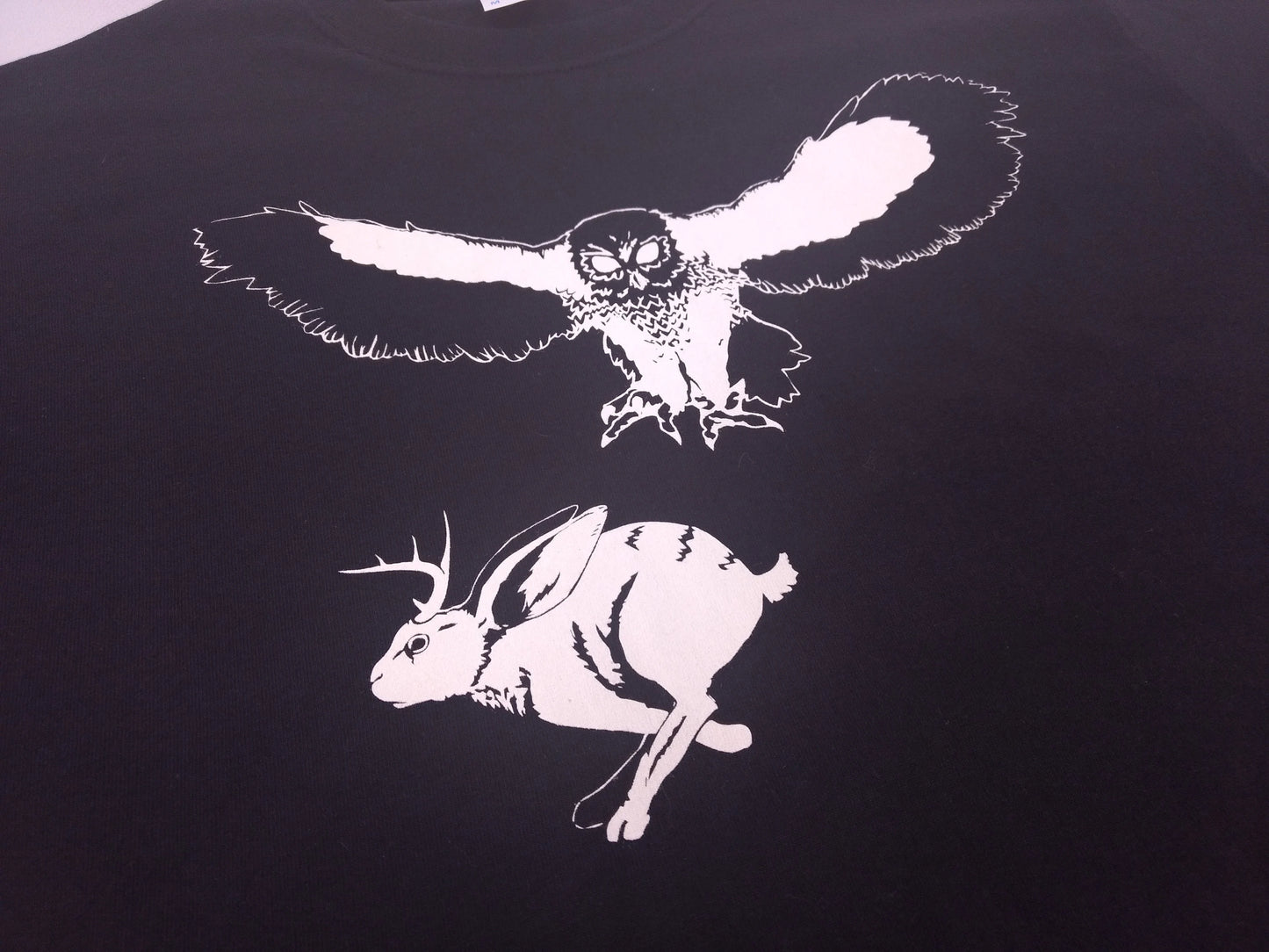 An illustration of an owl hunting a jackalope on a black  t-shirt