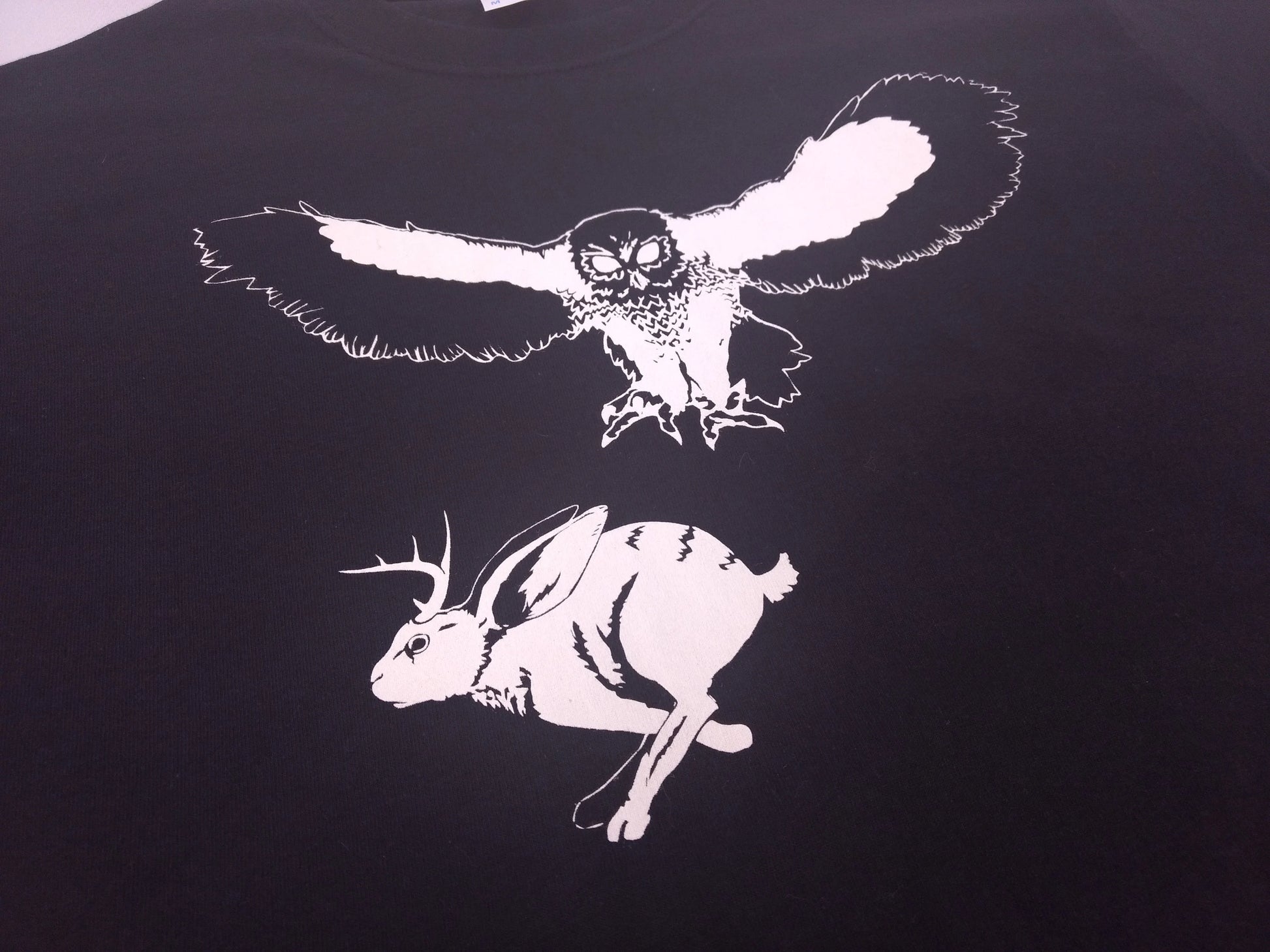 An illustration of an owl hunting a jackalope on a black  t-shirt